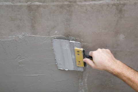 A man applying cement stucco on wall, illustrating stucco options in San Jose, CA