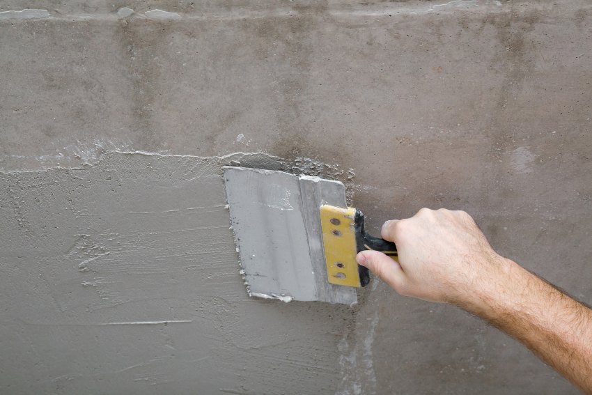 A man applying cement stucco on wall, illustrating stucco options in San Jose, CA